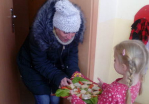 Dziewczynka trzymająca tacę z kanapkami częstuje mamę
